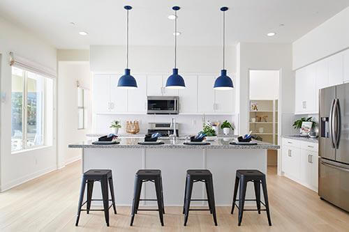kitchen with white cabinets, white tile backsplash and blue drum pendant lights