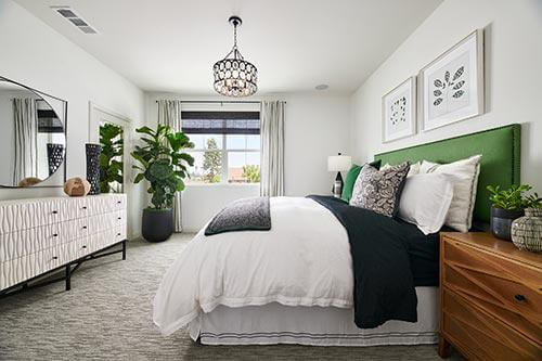 primary bedroom with white walls, green fabric headboard and textural furnishings