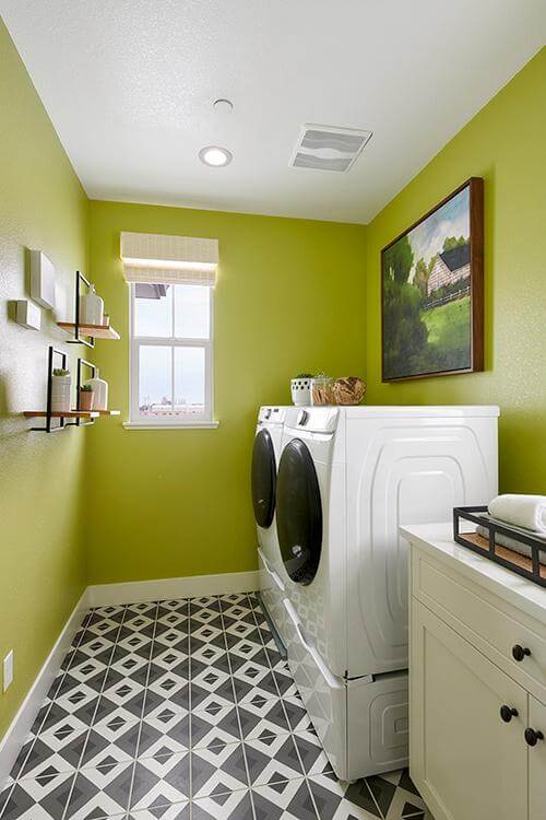 laundry room with green painted walls and black and while tile floor at Plan 1 Dover at Compass Bay in Newark, California