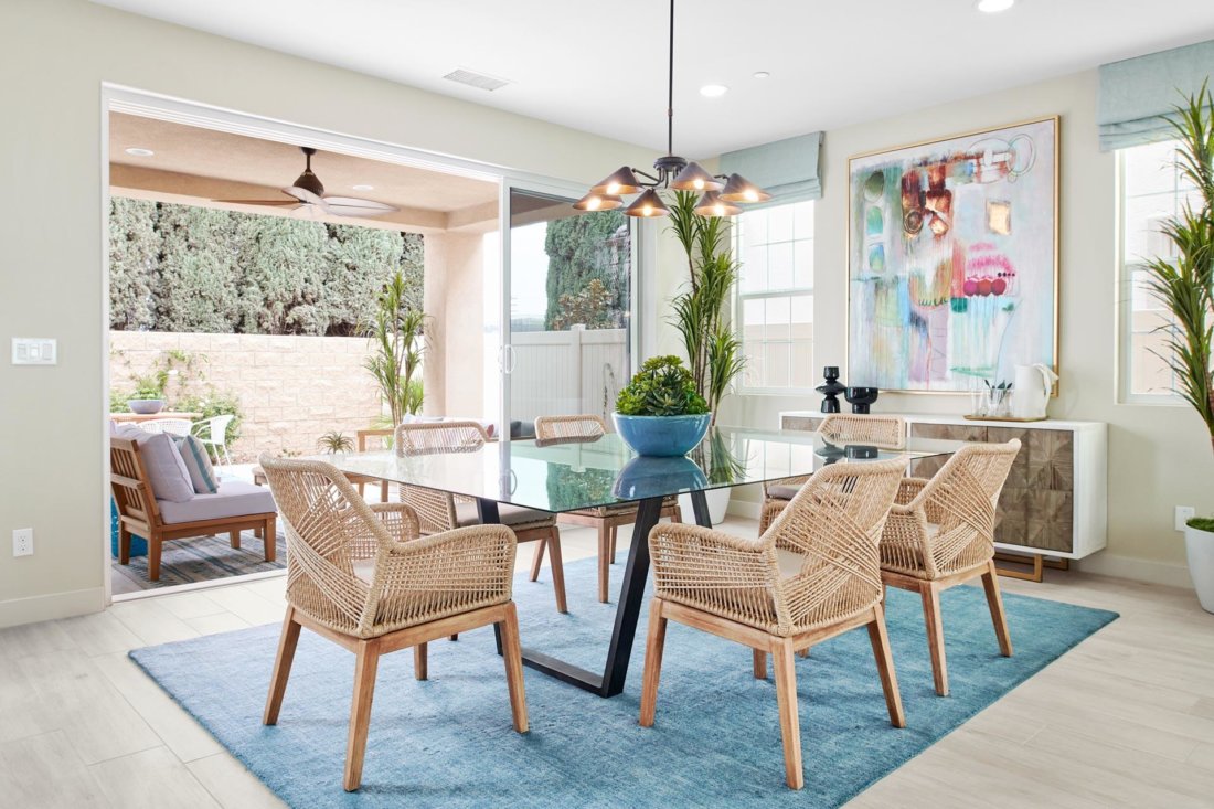 glass dining table and rattan chairs with large-format pastel abstract artwork Chateau Estates