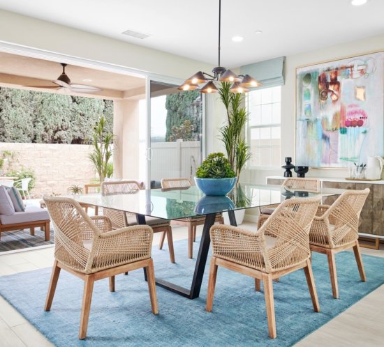 glass dining table and rattan chairs with large-format pastel abstract artwork Chateau Estates