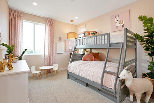 kids’ room with gray bunk beds and pale peach walls, bedding, and accents