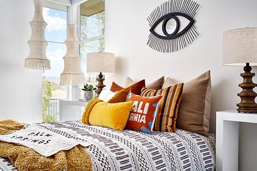boho themed bed with mustard, burnt orange, and brown pillows Flair