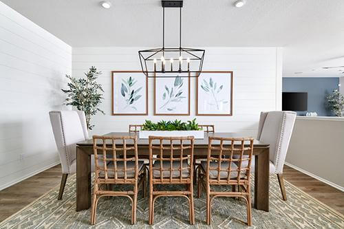 dining room with white shiplap walls, wood and rattan furnishings, and pale gray patterned area rug Rancho Palma Roija