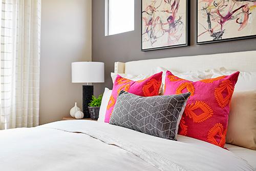 bed with black, hot pink, and orange printed pillows Center House