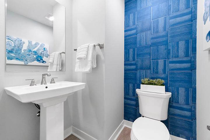 cobalt blue tile patterned wallpaper, white pedestal sink, mirror, toilet in powder room Townes
