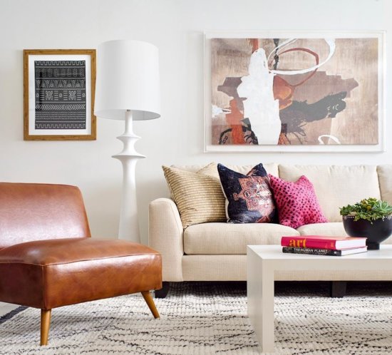 bright living room with a brown leather club chair, abstract art, and colorful throw pillows