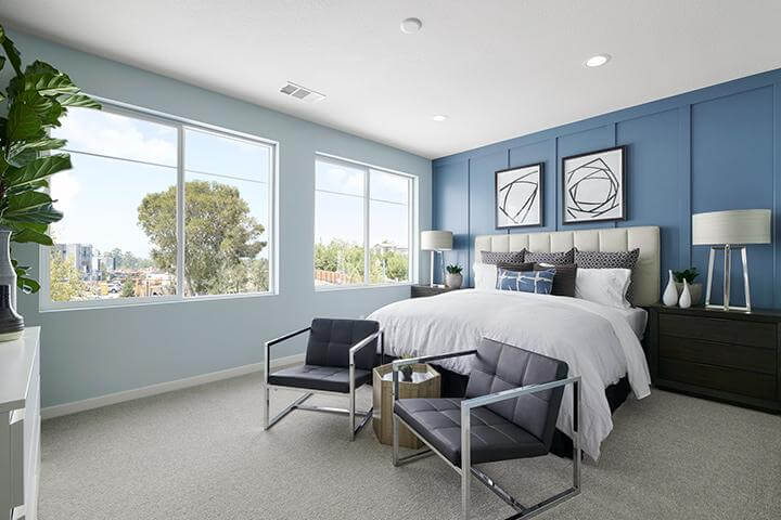 blue bedroom with modern artwork, large windows, and stylish chairs