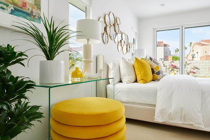 bright and cheery bedroom with yellow accents, mirrors, and plants