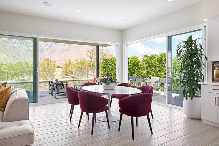 bright dining area with large windows and a sliding doors, maroon velvet chairs