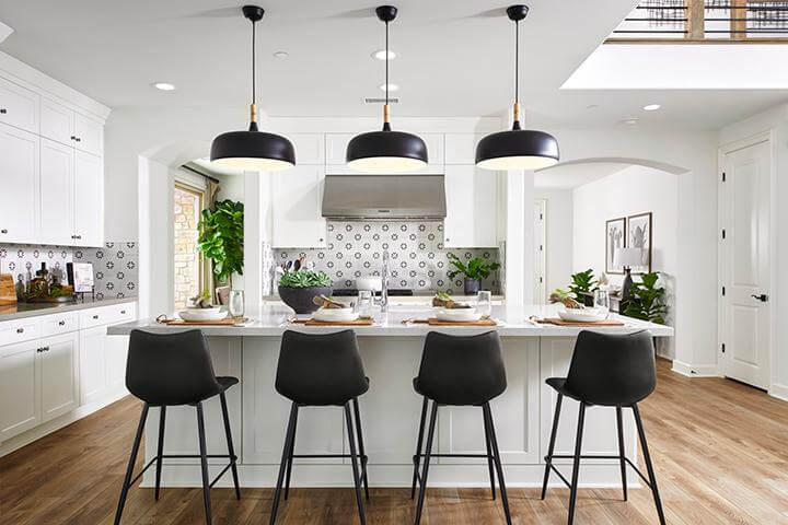 white kitchen with pendant lights, patterned backsplash, and leather bar stools
