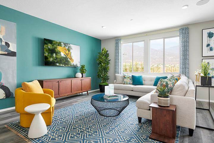 colorful living room with teal accent wall, blue rug, and modern yellow chair
