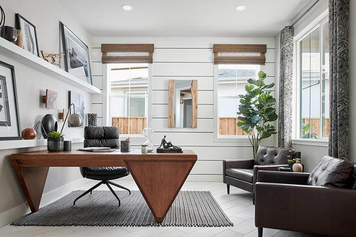 modern office with white shiplap and a leather accent desk and club chairs