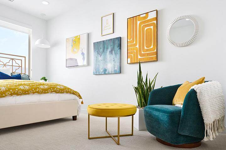 colorful yellow and teal bedroom with abstract artwork and velvet furniture