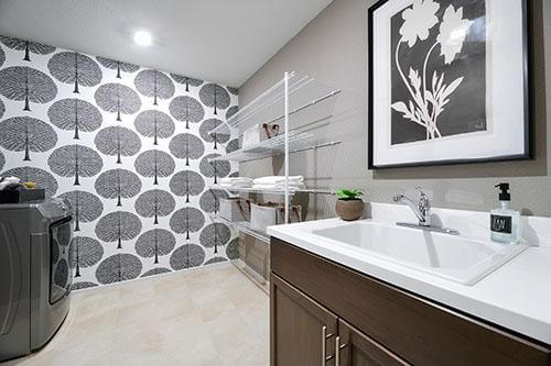 graphic wallpaper with neutral tones and dark vanity in laundry room