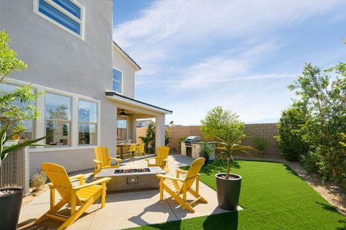 bright backyard with yellow lounge chairs and firepit