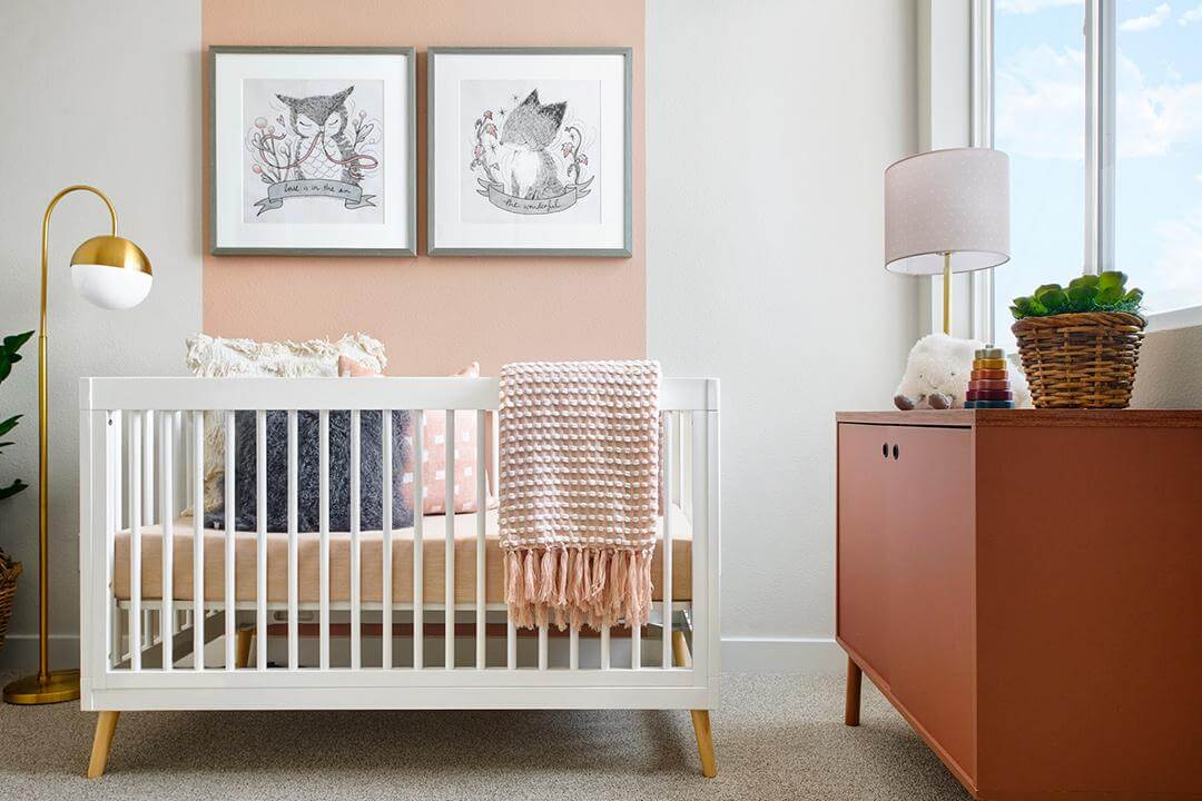 nursery with pink wall stripe and natural textures