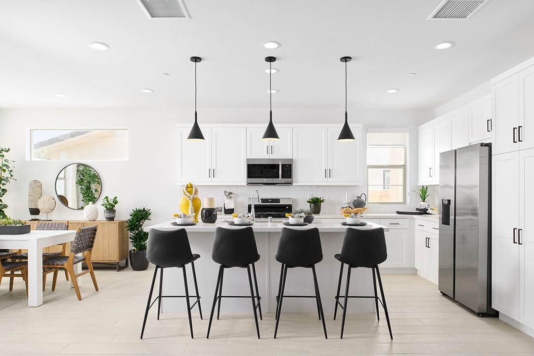 white kitchen with black barstools and modern pendant lighting