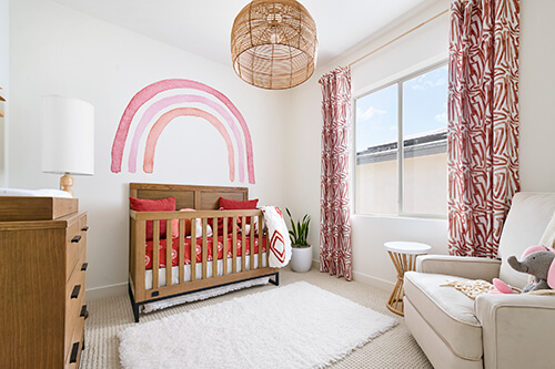 girls bedroom with pink rainbow wall and crib