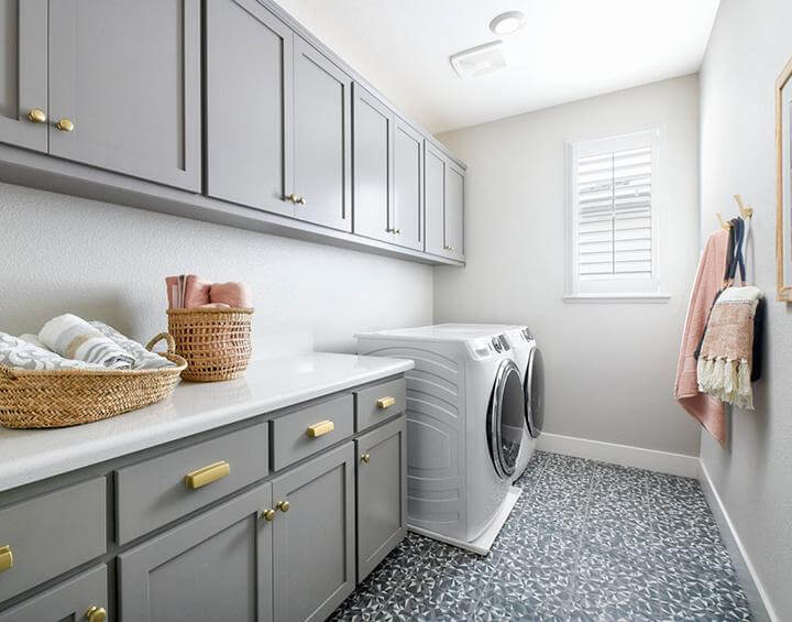 laundry room with gray cabinetry and gold hardware